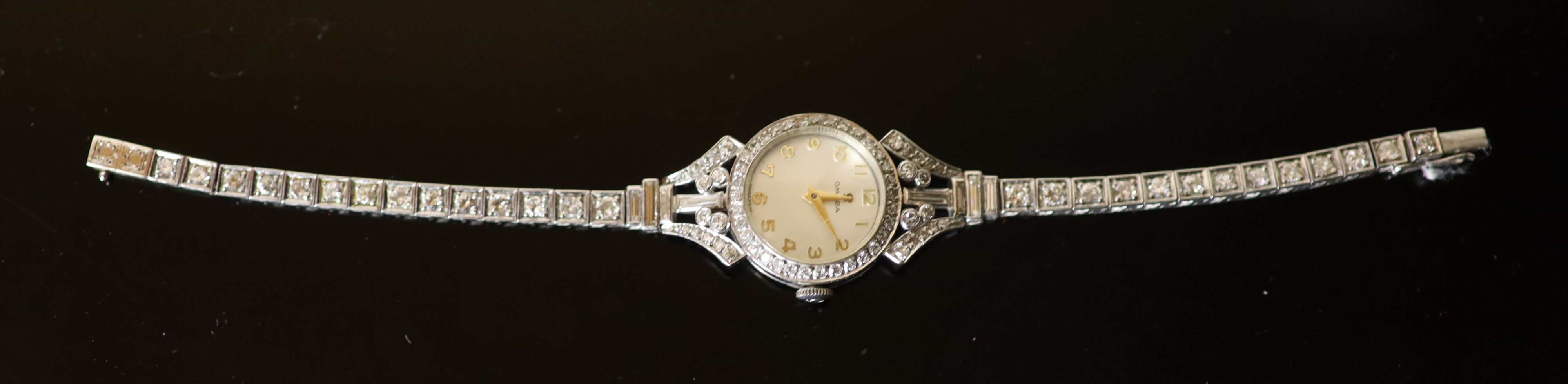 A ladys early 1960s 18ct gold, palladium and diamond set Omega manual wind cocktail watch, on diamond set bracelet,